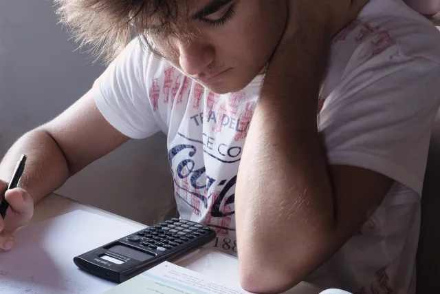 A student using a laptop and notebook for mathematics study.