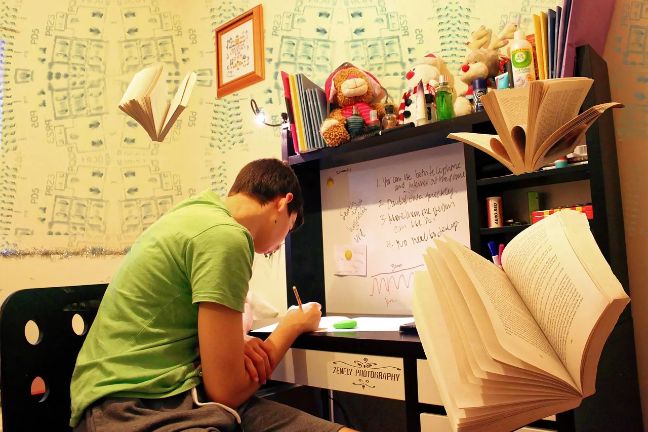 A student studying at a desk with a laptop and books for exam preparation