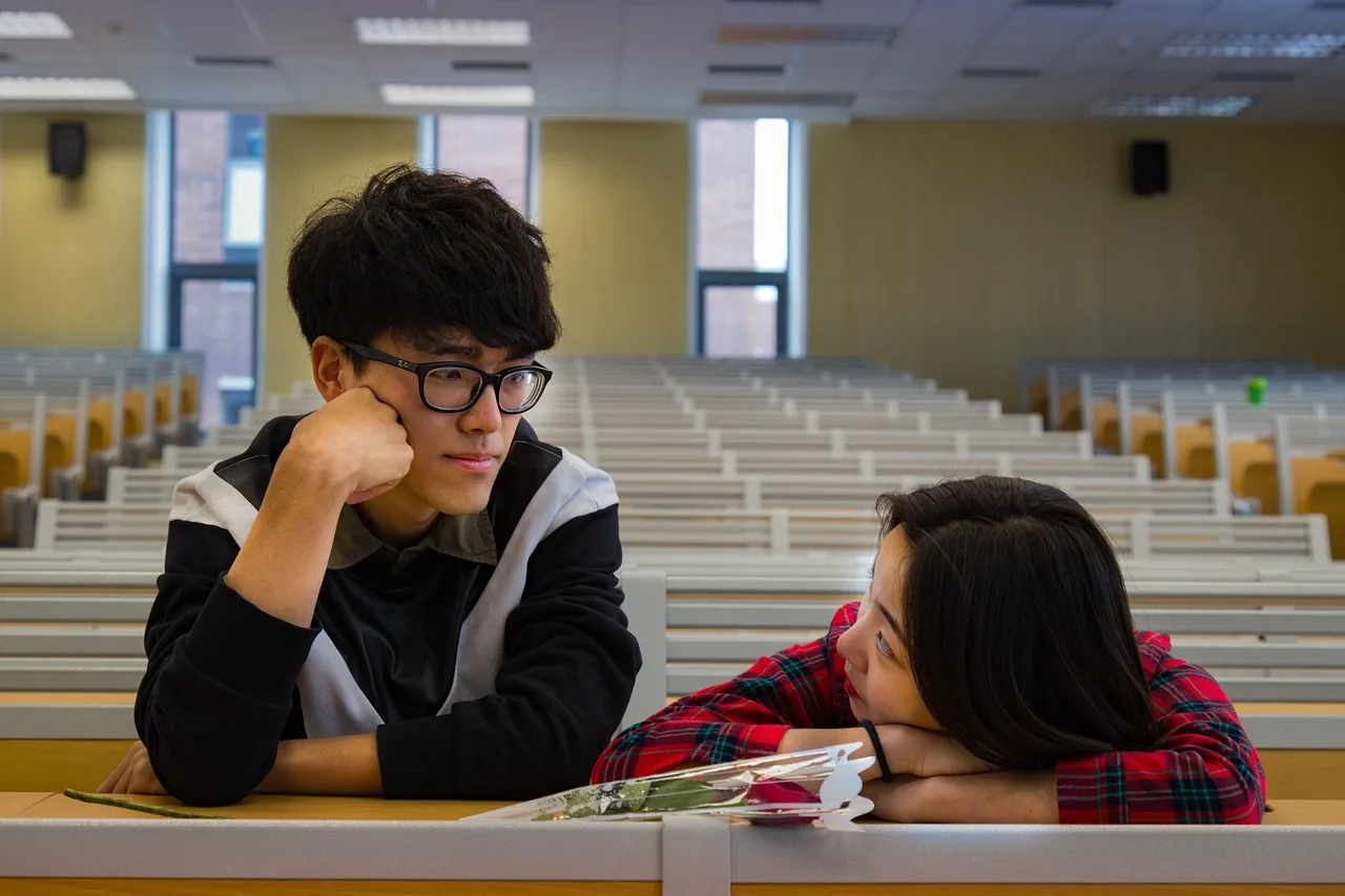University students in a lecture hall discussing academic policies on AI tools and laptop bans