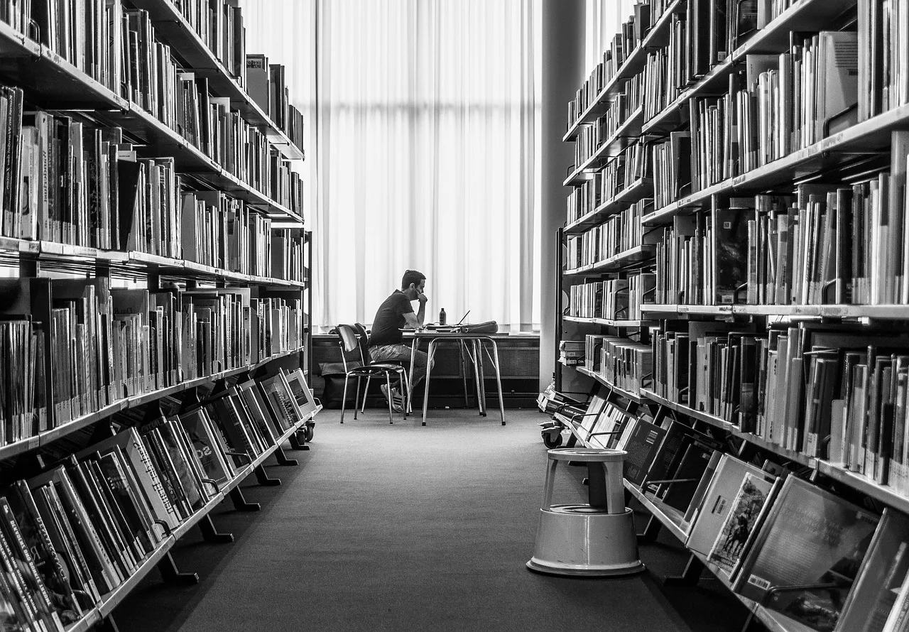 A student reviewing documents in a library while searching for international scholarship opportunities.