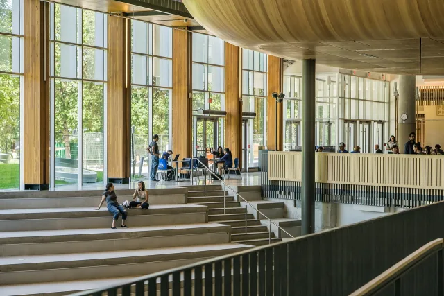 Students walking through a modern university campus building during the academic year